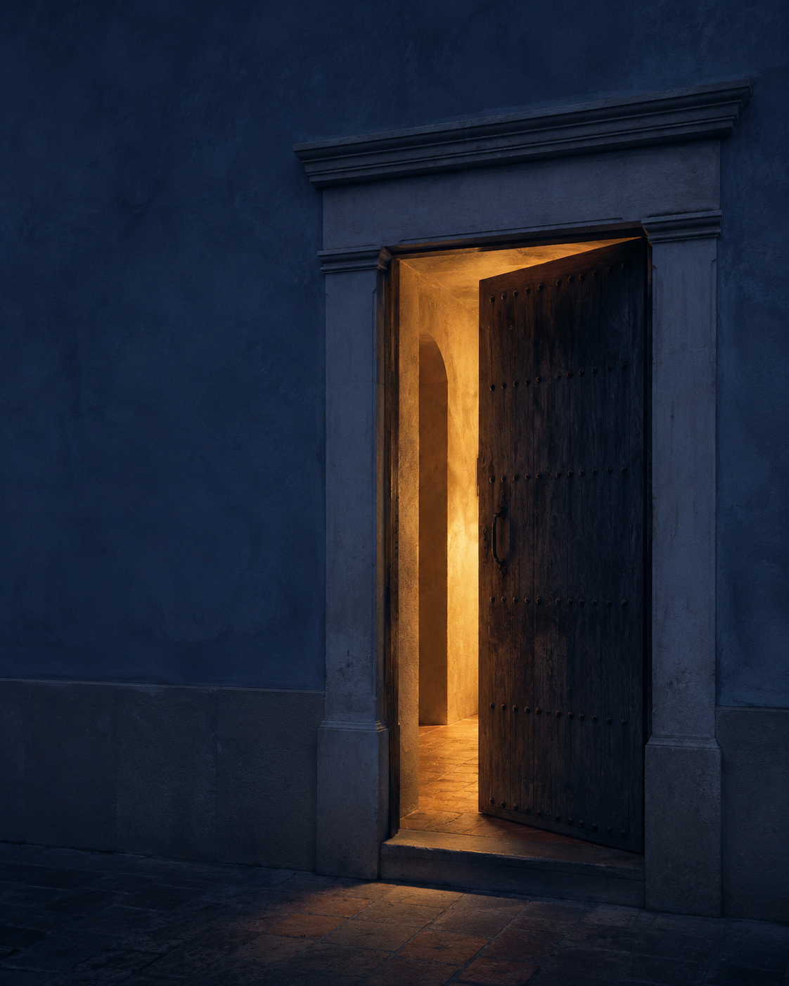 Wooden door ajar with warm golden light spilling onto a dark blue stucco wall